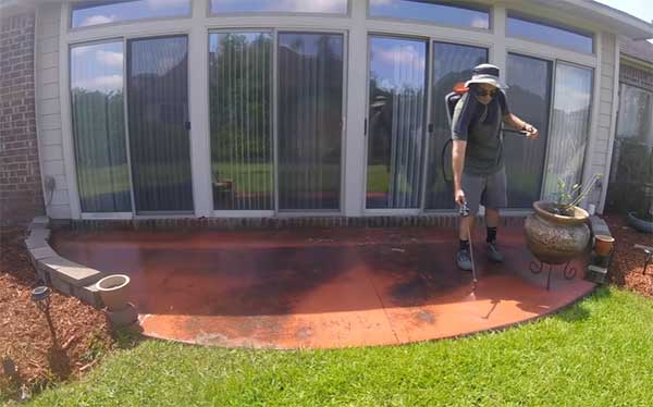spraying soap to the concrete patio